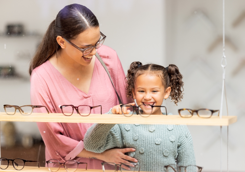 Mother and daughter at the optometrist choosing frames - Carrboro Eye Doctor Mother and daughter smile as they pick out new frames - Carrboro Eye Doctor